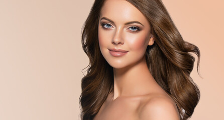 Naklejka premium Brunette girl with long and shiny curly hair . Beautiful model woman with wavy hairstyle 