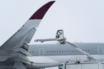 De-icing the aircraft before the flight. The deicing machine sprinkles the wing of a passenger...