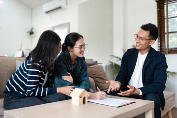 Real Estate Agent Assisting Young lgbt lesbian Couple with Signing Contract for New Home Purchase in Modern Living Room
