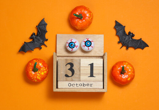 October 31 wooden calendar with Halloween decor on orange background