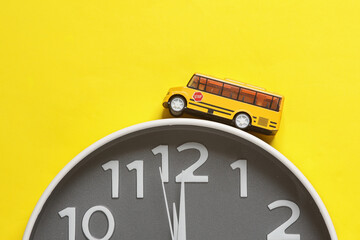 Large round clock with school bus on yellow background.