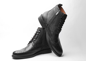 Stylish black leather men's brogue boots on a white background
