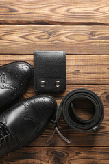 Men's black leather boots, wallet and belt on wooden background. Top vew