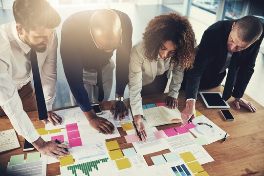 Business people, meeting and notes with documents, graphs and financial review at modern office. Woman, group and reading paperwork with discussion, charts and point for feedback with team at company