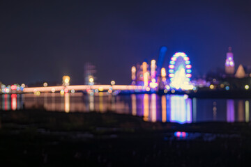 Blurry background image of event 'Sail Kampen' with colorful lighting and reflection in the river 'De IJssel'