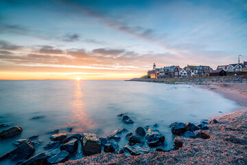 Sunset with a beautiful setting sun over the horizon near an old fishing village called Urk, with a heritage lighthouse