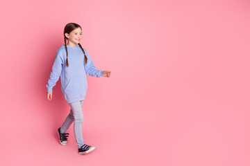 Full body portrait of cute little schoolkid walk empty space wear hoodie isolated on pink color background