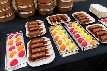 A selection of vibrant macarons and decadent chocolate eclairs artfully presented on transparent trays