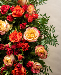 Part of a large bouquet of red, orange and yellow roses with green sprigs