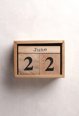 Wooden block calendar with date June 22 on white concrete background