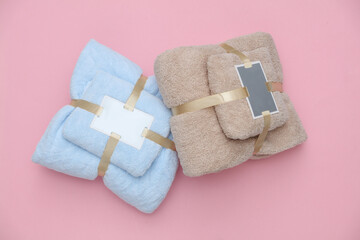 Set of towels with tag wrapped in ribbon on pink background