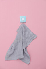 Kitchen towel hangs on a hook. Pink background
