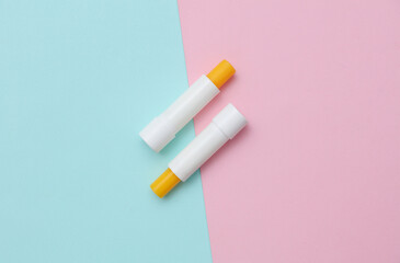 Lip balm tubes on blue pink background. Top view