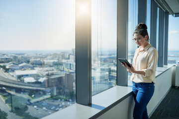 Tablet, office and businesswoman at window for reading, feedback and research in company. Journalist, woman and technology in city for review, updates and social media in corporate workplace