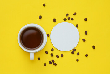 Mockup of white empty coaster and coffee cup, coffee beans on a yellow background. Top view