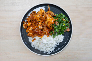 A plate of tomato garlic chicken and vegetables with steam rice.