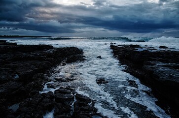 Wave crashes on stone coast line, West coast of Ireland, Dark stormy cloudy sky. World Oceans Day