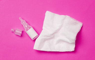 Eye drops bottle with napkins on pink background. Top view