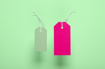 Blank clothing price tags or labels mockup with strings on green background. Sale, shopping concept. Top view
