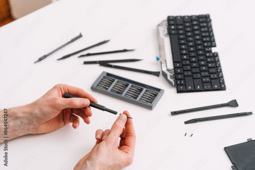Poster man install small size bit on screwdriver to fix parts of a computer keyboard
