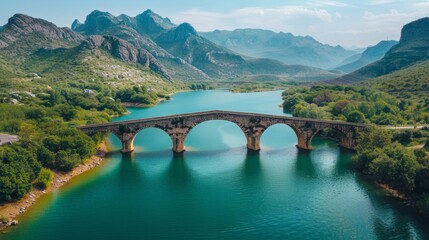 Ancient stone bridge over serene river in mountain landscape, connection concept. 