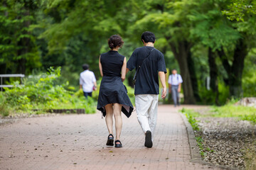 Obraz premium 公園で手をつないで歩く若い男女