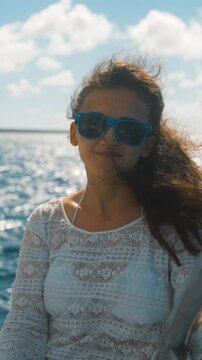4k UHD. Young pretty beautiful girl in sunglasses sitting on the edge of the yacht among the blue amazing caribbean sea. Saona island. teal and orange style. Smile happiness. Brownhair. Sunny, sunrise