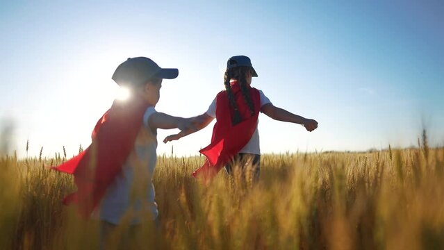 A group of kids playing a video game of superheroe together. Child hero fun concept. Superhero running through the wheat with children. A group of sunset kids playing a game of running together.