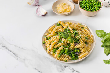 Vegetarian pasta with boiled green peas and basil on plate
