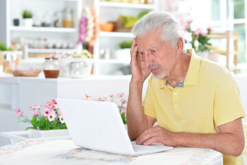 Portrait of senior man with laptop at home