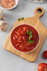Canned whole peeled tomatoes with juice and parsley on table