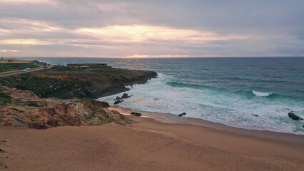 Aerial rocky sea shore washed by foamy water at evening dusk. Coastal cliffs