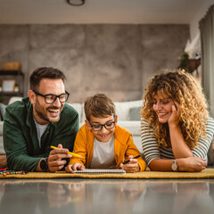 Family of three lie down on the carpet and draw at home together