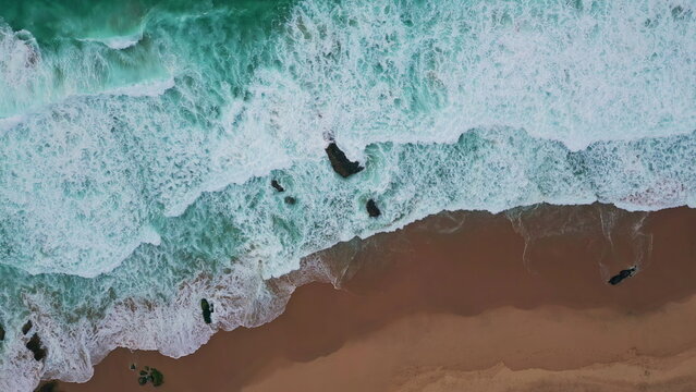 Turquoise surf splashing coast making foam aerial view. Ocean waves patterns 