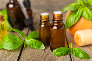 Basil essential oil on a textured wooden background. Basil essential oil and fresh leaves. Aromatherapy. Aroma oil. Medical herbs. Alternative medicine. Place for text. Copy space.