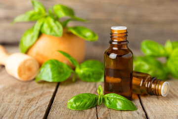 Basil essential oil on a textured wooden background. Basil essential oil and fresh leaves. Aromatherapy. Aroma oil. Medical herbs. Alternative medicine. Place for text. Copy space.