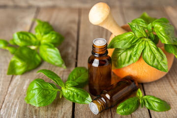 Basil essential oil on a textured wooden background. Basil essential oil and fresh leaves....