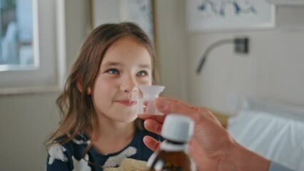 Sick child taking medicine at white bedroom closeup. Mom giving mixture to kid