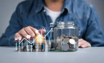Closeup of stacked coin growth chart and glass jar with coin. Man calculating financial planning. Money saving concept, investment, emergency money, pension, insurance, interest or dividend.