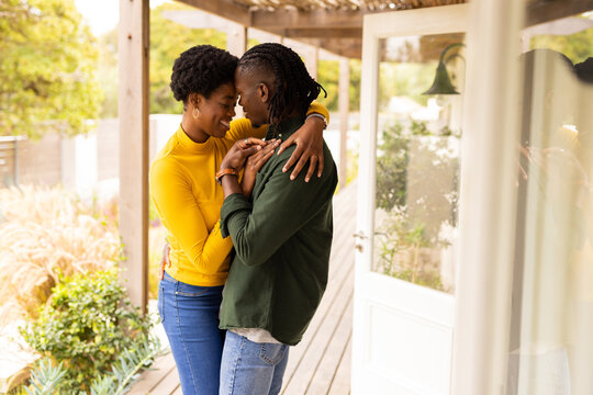 Embracing lovingly on porch, African American couple enjoying intimate moment together