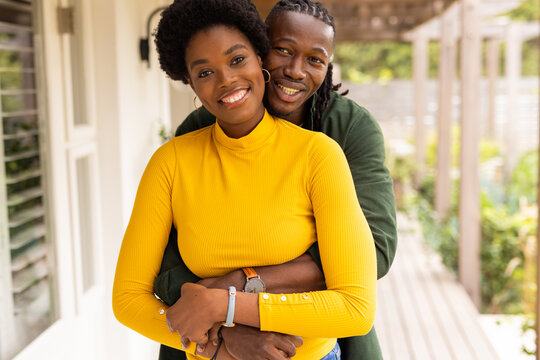 Outdoors, African American couple embracing and smiling, enjoying time together at home