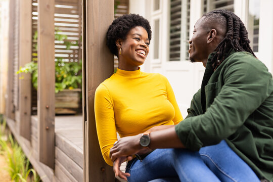 African American couple sitting on porch, smiling and enjoying conversation together