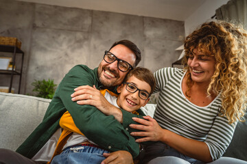 Portrait of mum,dad and son sit on sofa and have family time at home