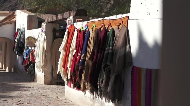 Traditional souvenir sales business displays native Argentine clothing on the exterior wall. Poncho. Purmamarca, Jujuy.
