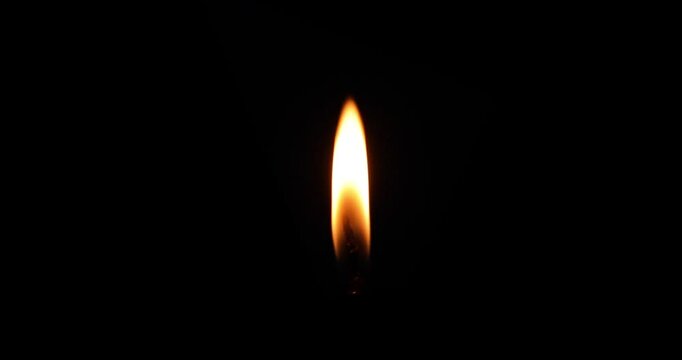 Close-up of a brightly lit candle flame on a dark background. - Powered by Adobe