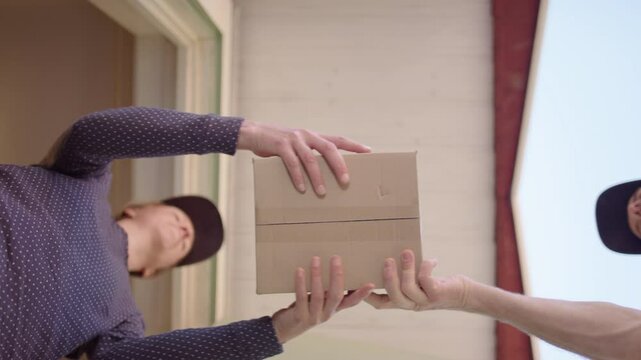 Female customer takes online shopping package from courier guy, upward view