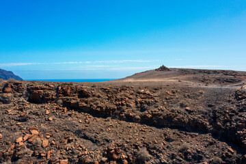 Rugged Volcanic Landscape of Fuerteventura with Ocean Vista. Arid Terrain and Rocky Outcrop Showcase Canary Island's Dramatic Geology.