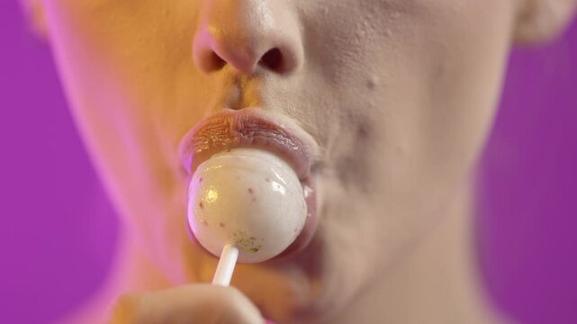 Cute caucasian woman sucks on white lollipop, concept oral sex, close-up face
