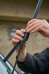 man installs the windshield wipers of the car, a man's hands install a windshield wiper on the windshield of a car, Car service concept