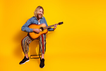Fototapeta premium Full body photo of attractive young man play acoustic guitar singing dressed stylish denim clothes isolated on yellow color background